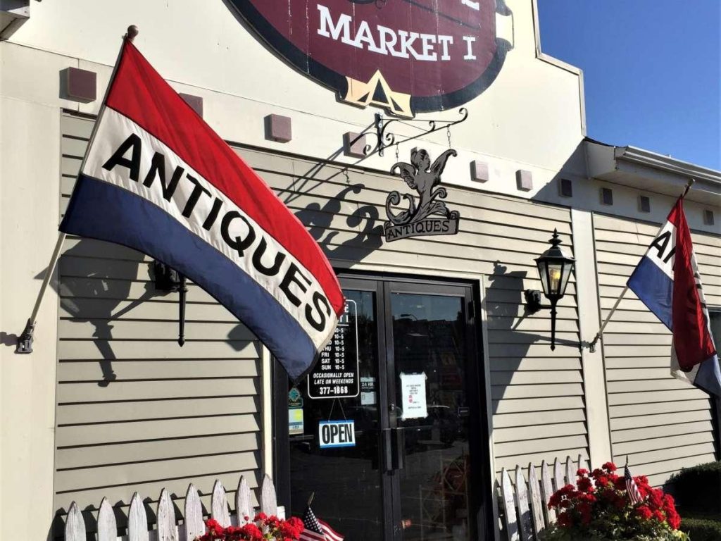 Front entrance of St Charles Antique Mall with antique signage and flags outside the building
