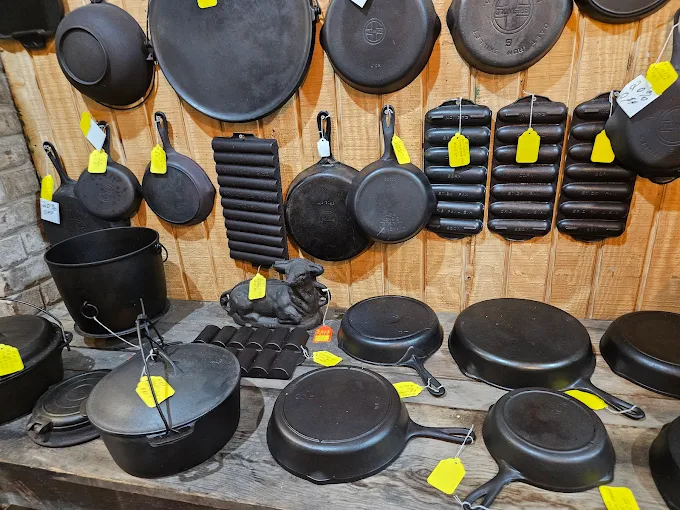 Collection of antique cast iron skillets and cookware displayed at Highway Pickers indoor flea market