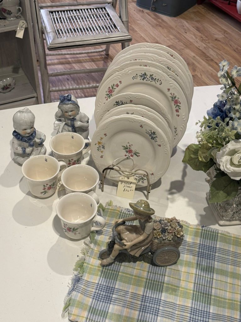 Vintage porcelain tea set and collectible plates displayed at Highway Pickers flea market vendor booth