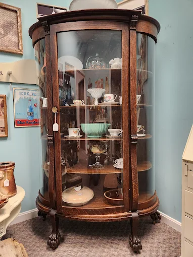 Antique wooden display cabinet filled with vintage glassware and collectibles at Two Crows Antique Mall in Ranson WV.
