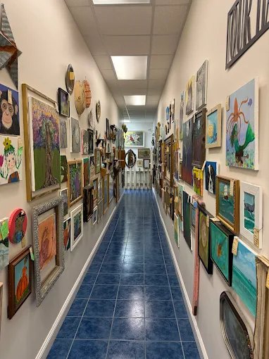 Long hallway lined with vintage paintings and framed artwork inside Two Crows Antique Mall in Ranson WV.