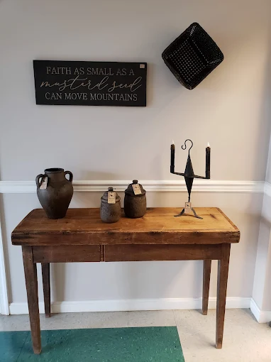 Primitive wooden table with vintage pottery and decorative antiques displayed at Two Crows Antique Mall in Ranson WV.