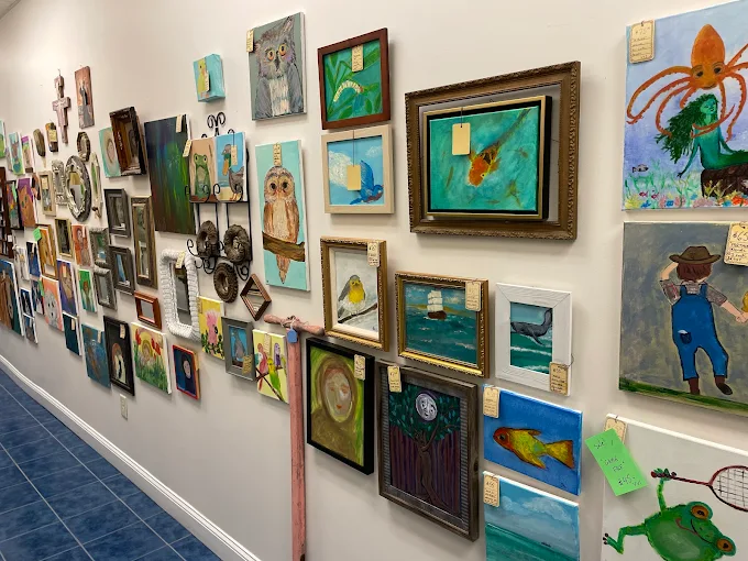Wall filled with colorful vintage artwork and framed paintings inside Two Crows Antique Mall in Ranson West Virginia.