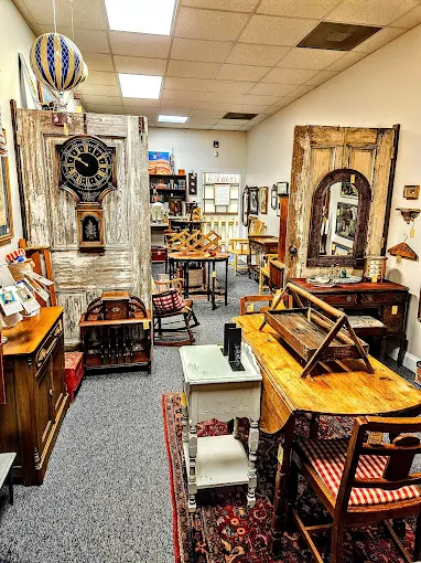 Room filled with vintage furniture, antique clocks, and decorative collectibles at Two Crows Antique Mall in Ranson West Virginia.
