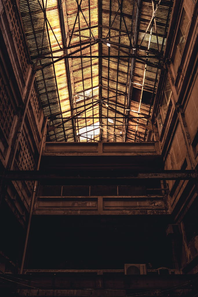 A low angle view of the interior of an abandoned warehouse featuring intricate steel architecture.