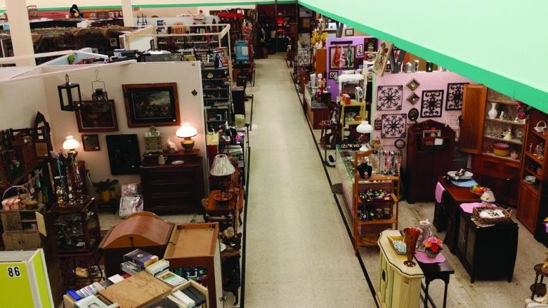 Antique mall interior with wide aisles, vintage furniture, and glassware displays