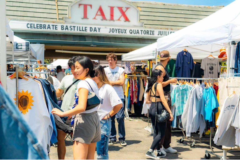 Shoppers browsing vintage clothing vendors outside the historic Taix building at Silverlake Flea