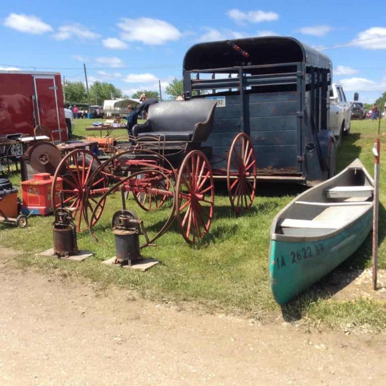 Antique wagon wheels, vintage farm equipment, and canoe displayed by vendors at Rutledge Flea Market in Rutledge Missouri