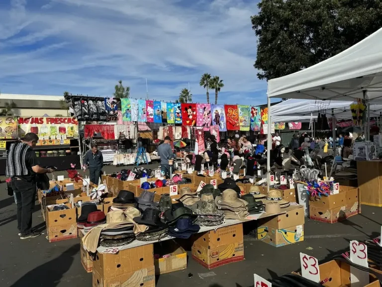 Vendor stalls selling hats, towels, and merchandise at Cypress College Swap Meet in Cypress, CA